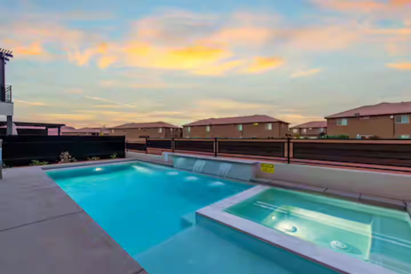 Pool at dusk featuring a residential view, a pool with connected hot tub, and a patio