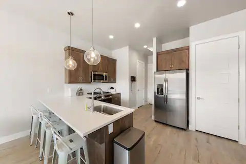 Kitchen with a kitchen bar, stainless steel appliances, pendant lighting, light countertops, and a peninsula