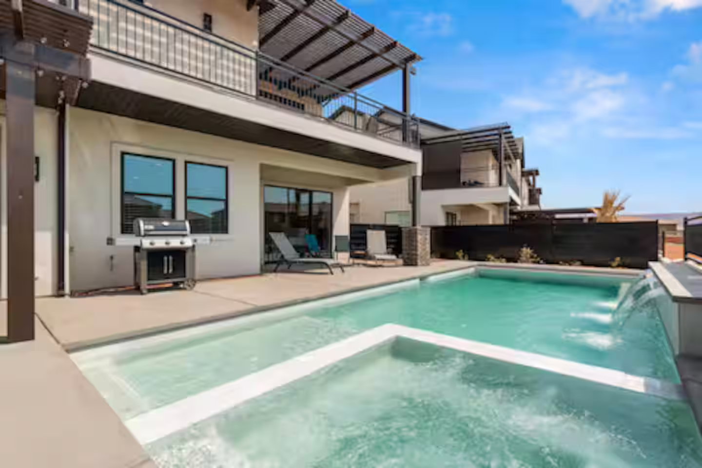 View of pool featuring a pool with connected hot tub, a grill, a patio area, and a balcony