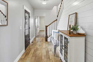 Foyer entrance featuring stairs, light wood-style floors, and wooden walls