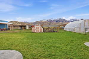 View of yard featuring an outdoor structure, a mountain view, and an exterior structure, shed and greenhouse