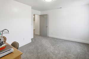 Office area or guest bedroom or playroom with light carpet and baseboards