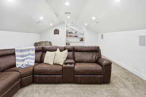 Home theater room featuring carpet, built in shelves, vaulted ceiling, and recessed lighting