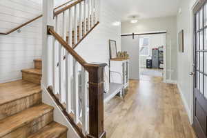 Staircase with a barn door and hardwood / wood-style floors