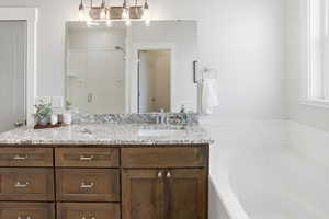 Full bath with a stall shower, vanity, and a garden tub