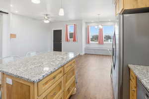ADU Kitchen with stainless steel appliances, light stone counters, pendant lighting, a kitchen island, and dark wood-type flooring