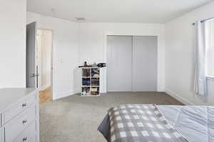 Bedroom with light carpet and a closet
