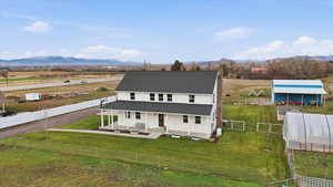 View of front of property featuring covered porch, a fenced backyard, a rural view, a chimney, and a mountain view