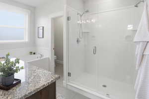 master bathroom featuring light tile patterned flooring, vanity, a dual shower stall, and a bath