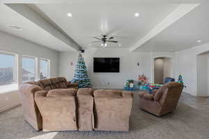 Living area with arched walkways, ceiling fan, light colored carpet, and recessed lighting