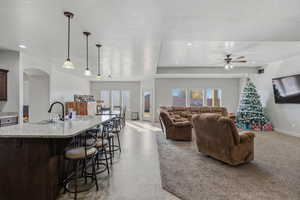 Living room featuring healthy amount of natural light, a textured ceiling, ceiling fan, light colored carpet, and recessed lighting