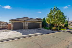 View of front of house featuring stucco siding, concrete driveway, a garage, a gate, and stone siding