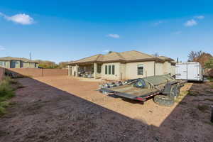 Rear view of house featuring stucco siding, a storage unit, a fenced backyard, and a patio area