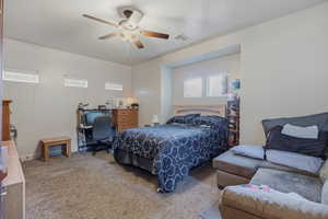 Bedroom with carpet floors, a ceiling fan, and an office area