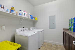 Laundry room featuring electric panel, washer and clothes dryer, and stone finish flooring