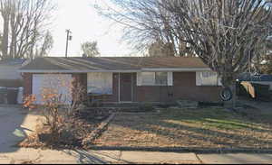Ranch-style house with brick siding, covered porch, and driveway