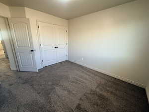 Unfurnished bedroom featuring carpet flooring and a closet