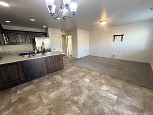 Kitchen featuring dark brown cabinetry, a peninsula, stainless steel appliances, open floor plan, and light colored carpet