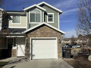 View of front of property featuring stone siding, concrete driveway, and a garage