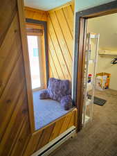 Bedroom with carpet floors, a baseboard heating unit, a textured ceiling, and wooden walls