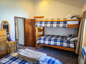 Bedroom with vaulted ceiling, a textured ceiling, and baseboard heating