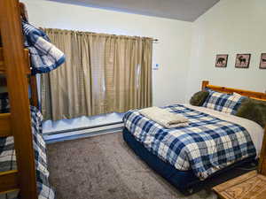 Bedroom featuring carpet, baseboard heating, and a textured ceiling