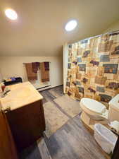 Bathroom featuring vanity, dark wood-type flooring, a shower with curtain, and a baseboard radiator