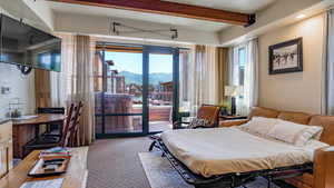 Bedroom with beamed ceiling, carpet, access to exterior, and a mountain view
