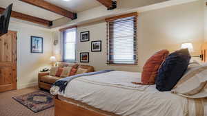 Bedroom with carpet flooring and beam ceiling