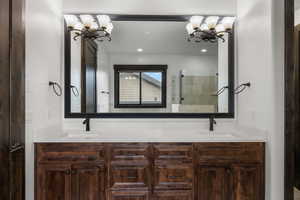 Full bathroom with double vanity, a stall shower, and a chandelier