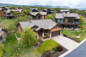 View of front of property with driveway, an attached garage, a residential view, and stone siding