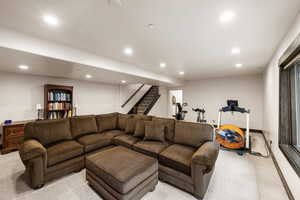 Carpeted living area featuring recessed lighting and stairs