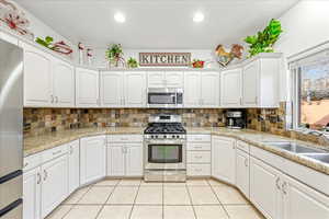 Kitchen with white cabinets, appliances with stainless steel finishes, tasteful backsplash, and recessed lighting