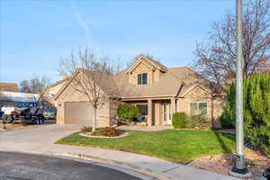View of front facade featuring stone siding, a front lawn, driveway, and a garage