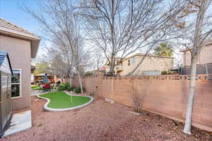 Fenced backyard featuring a patio area, an area to practice putting, and a residential view