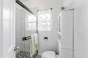 Full bath featuring a shower stall and toilet