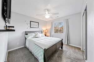 Carpeted bedroom featuring a ceiling fan and a closet