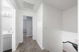 Hallway featuring carpet and an upstairs landing