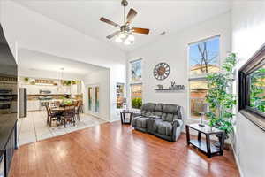 Living area featuring a ceiling fan, light wood-type flooring, and a towering ceiling