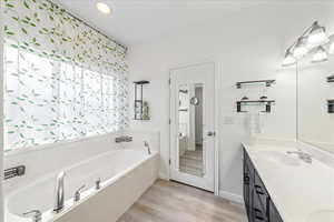 Bathroom featuring double vanity, a garden tub, and light wood-style floors