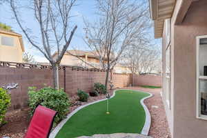 Fenced backyard with a putting green