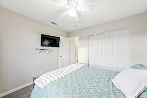 Carpeted bedroom with ceiling fan and a closet