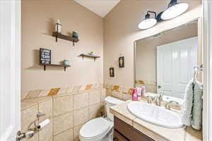 Half bathroom with vanity, tile walls, and a wainscoted wall