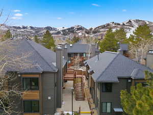 View of front facade with stairway, a chimney, a shingled roof, and a mountain view
