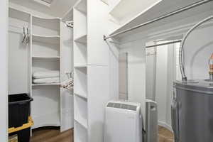 Walk in closet featuring water heater and dark wood finished floors