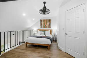 Bedroom with lofted ceiling, wood finished floors, and recessed lighting