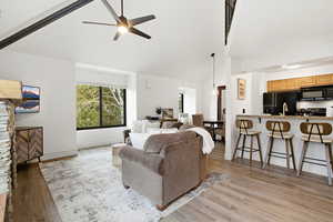 Living room featuring vaulted ceiling, a ceiling fan, and light wood-type flooring
