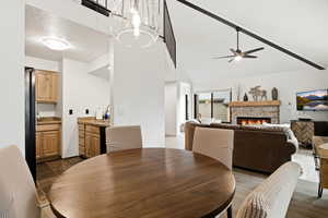 Dining room featuring a fireplace, high vaulted ceiling, a textured ceiling, and a ceiling fan