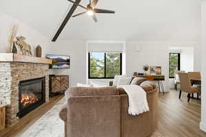 Living area featuring wood finished floors, a stone fireplace, and plenty of natural light