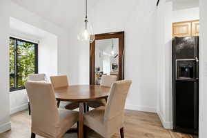 Dining room with light wood-style floors and vaulted ceiling